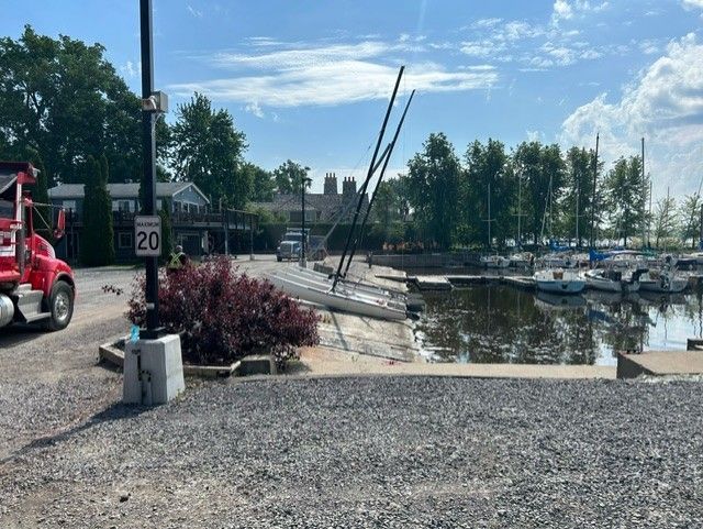 Un camion rouge est garé dans un terrain de gravier à côté d'une marina.