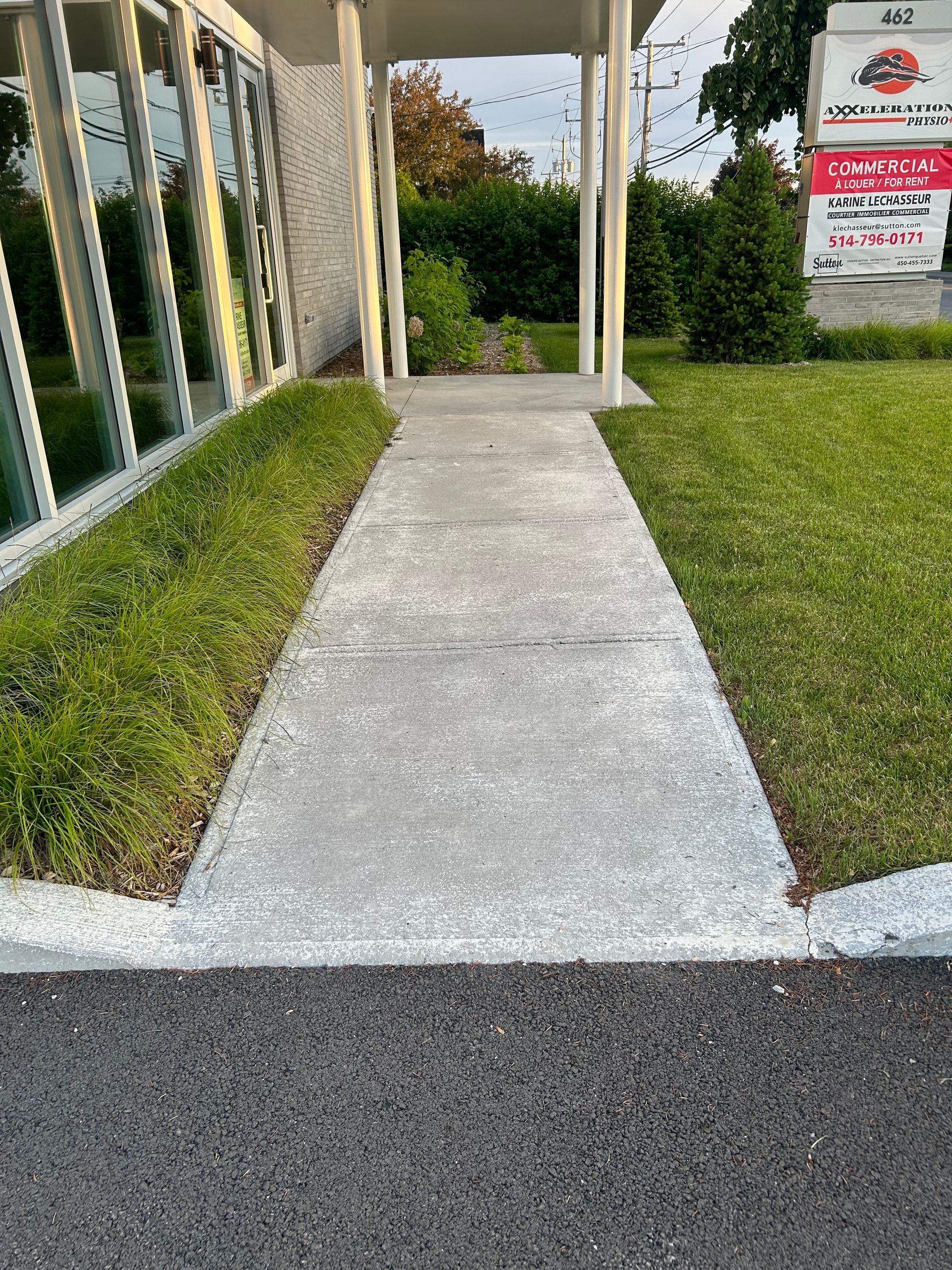 Une passerelle en béton menant à un bâtiment avec une pancarte en arrière-plan.