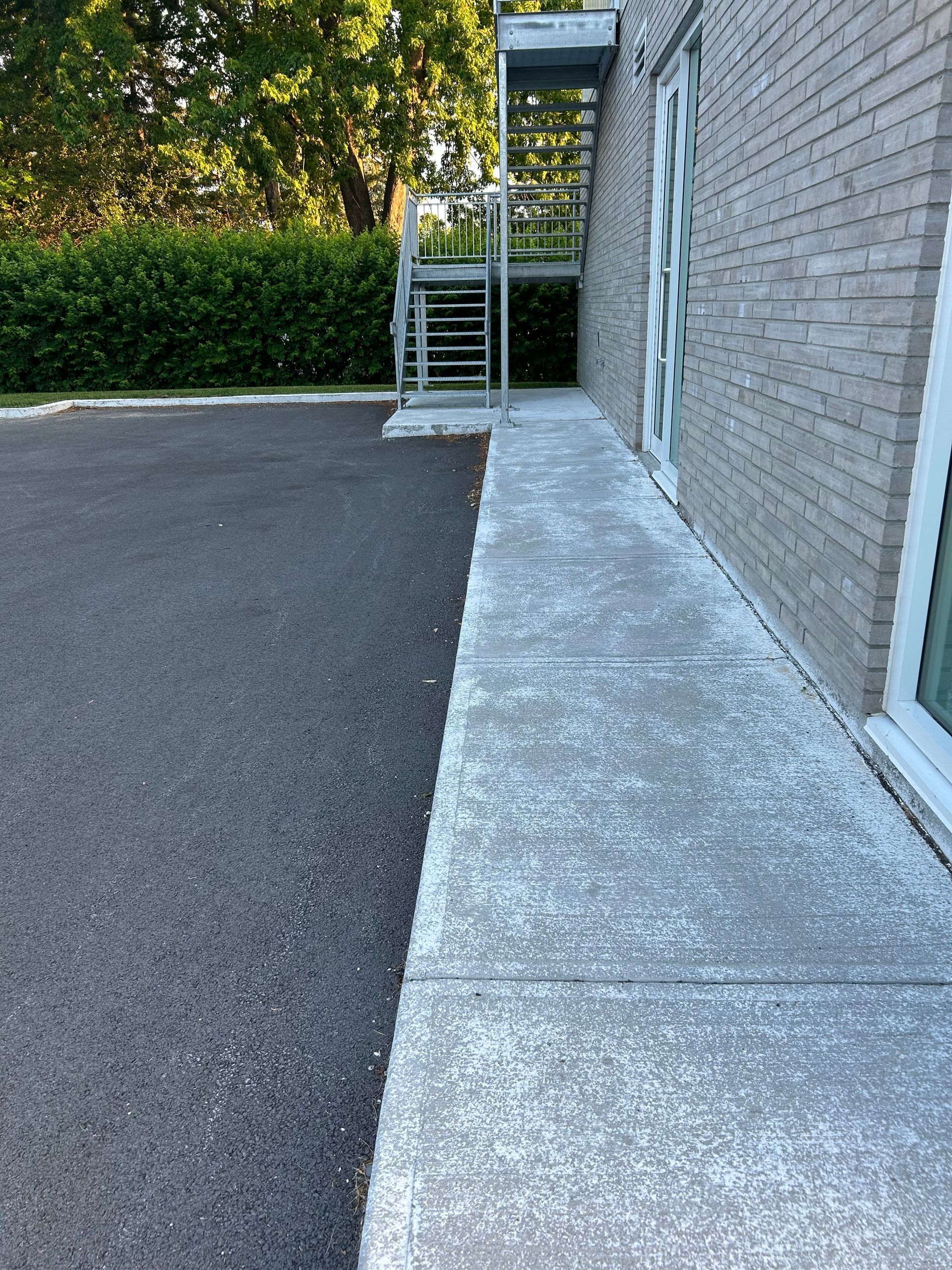 Un trottoir à côté d'un bâtiment en brique avec des escaliers qui y mènent.