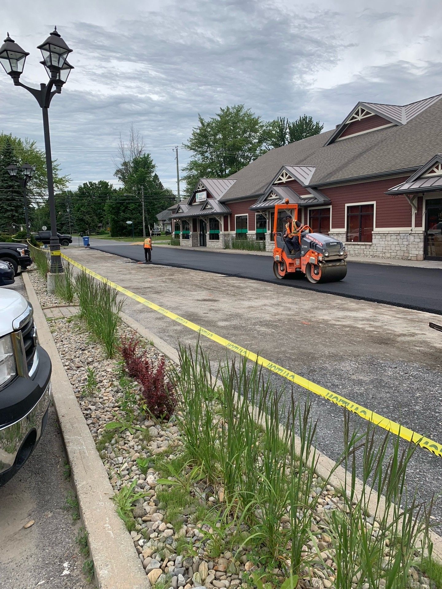 Un rouleau roule de l'asphalte dans une rue devant un immeuble.