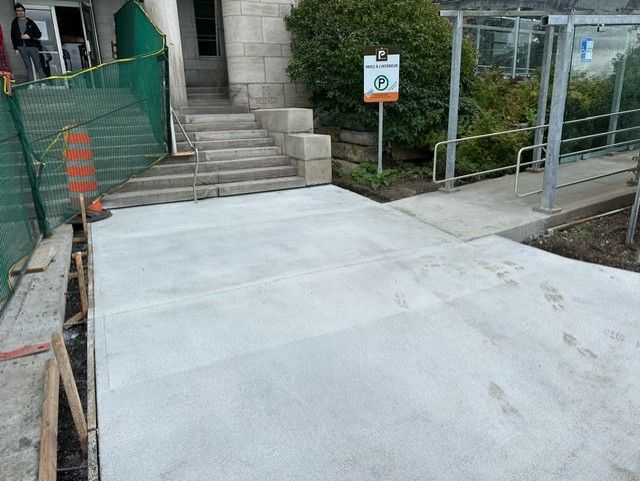 Une passerelle en béton est en cours de construction devant un bâtiment.