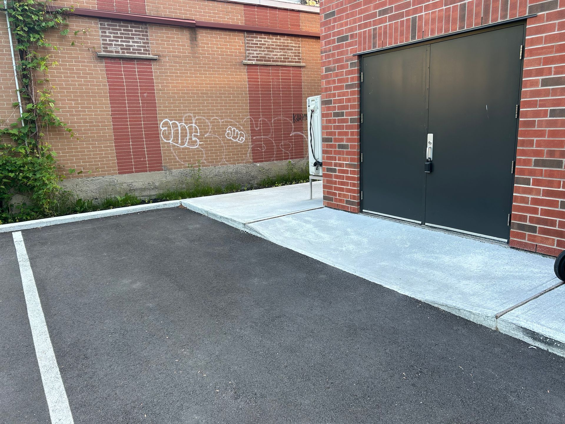 Un parking devant un immeuble en brique avec une porte de garage noire