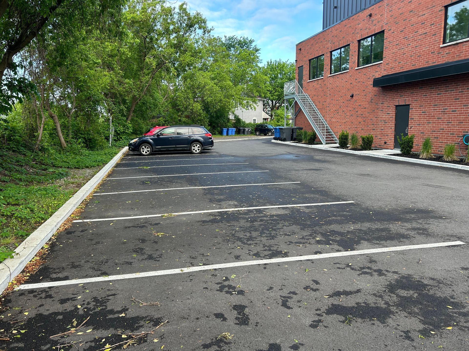 Un parking avec des voitures garées devant un bâtiment en brique.