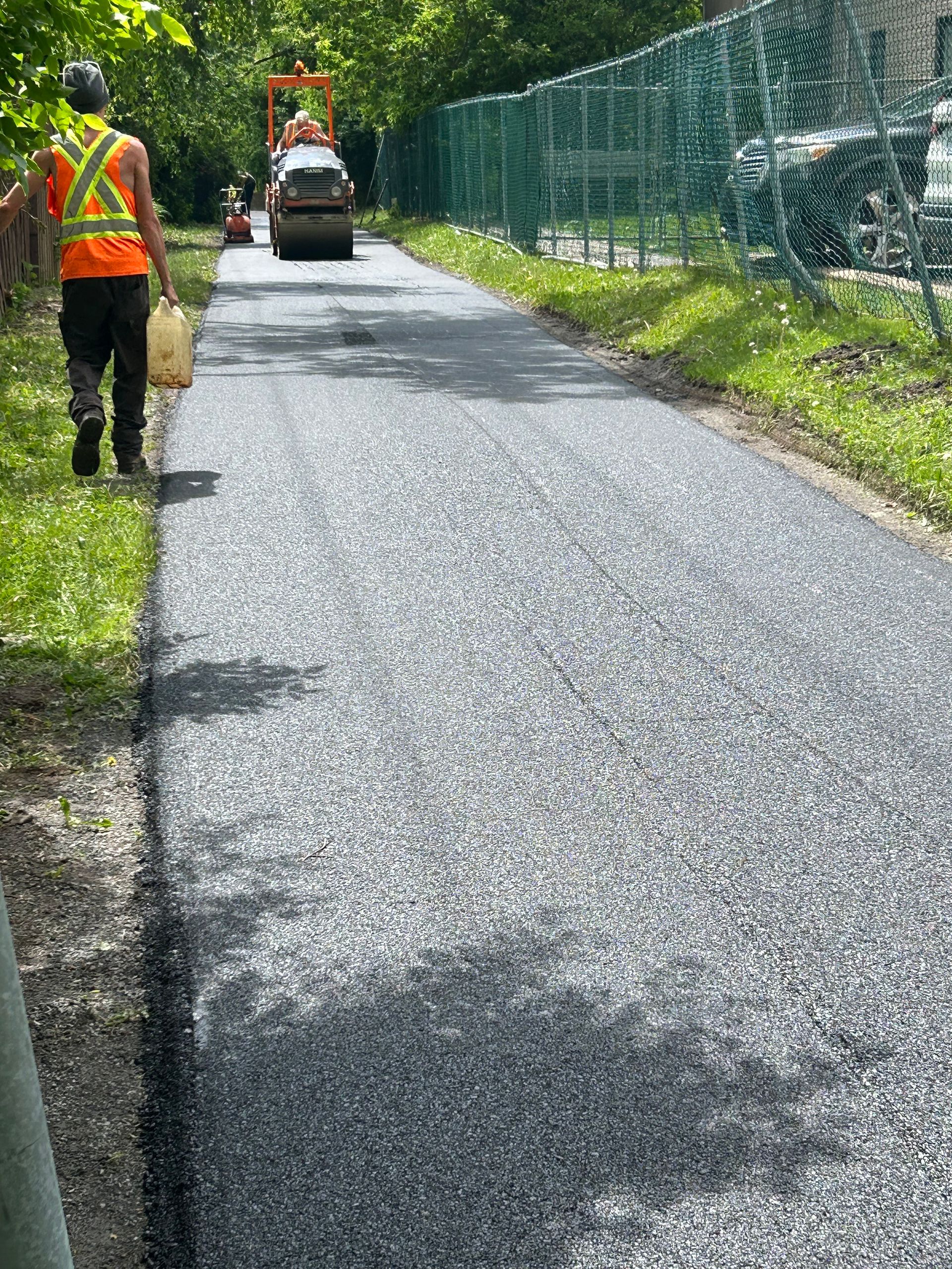 Un homme marche sur une route à côté d'un rouleau.