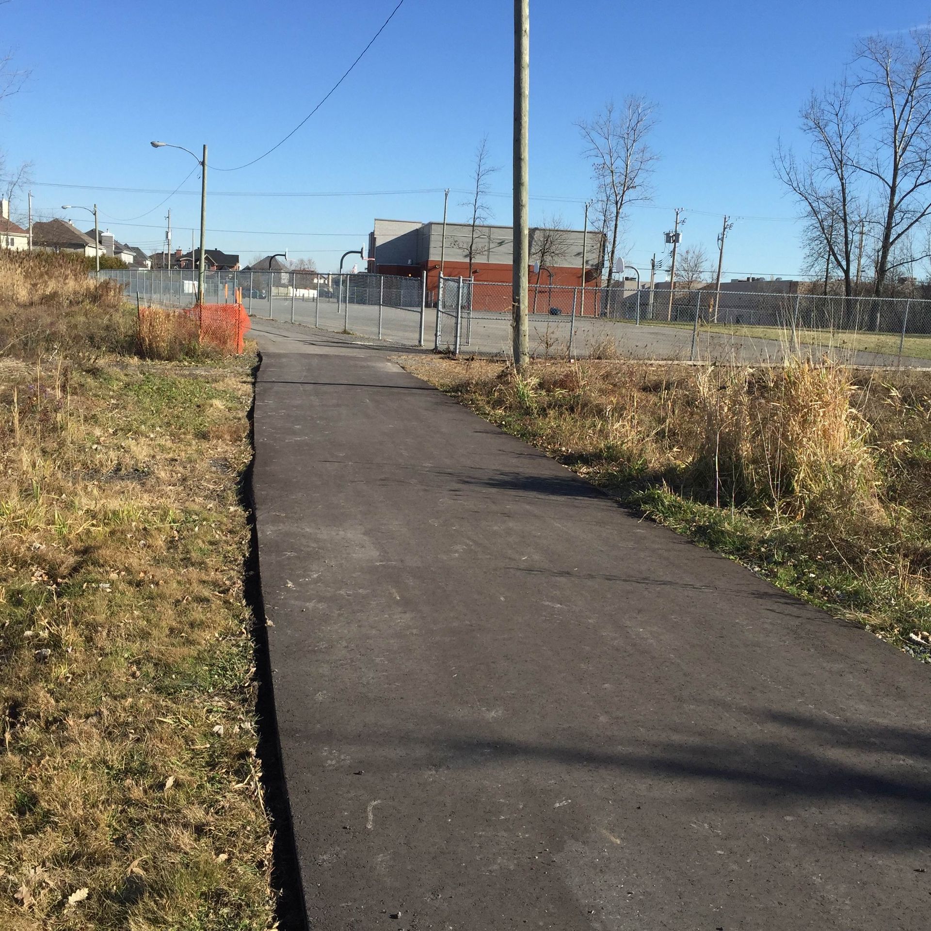Un chemin traversant une zone herbeuse avec un bâtiment en arrière-plan