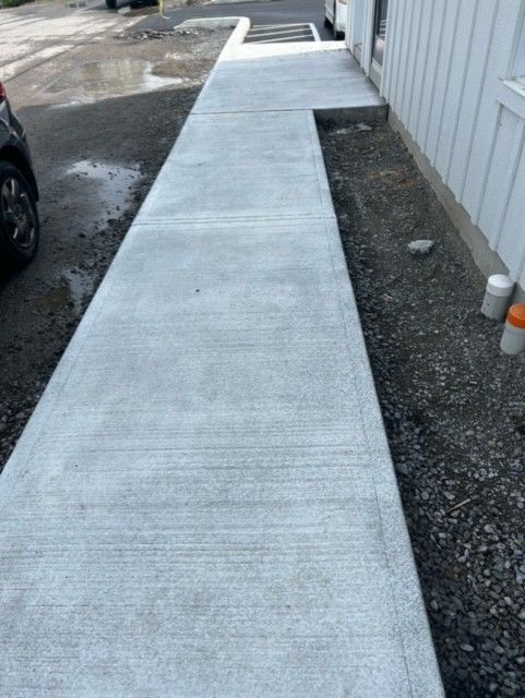 Une passerelle en béton menant à un bâtiment avec une voiture garée sur le côté.