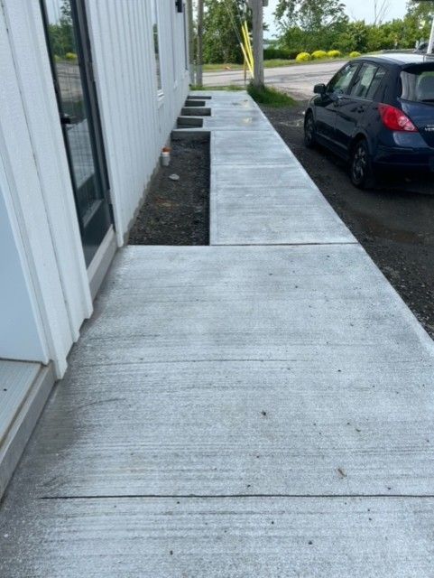 Une voiture bleue est garée sur un trottoir à côté d'un immeuble.