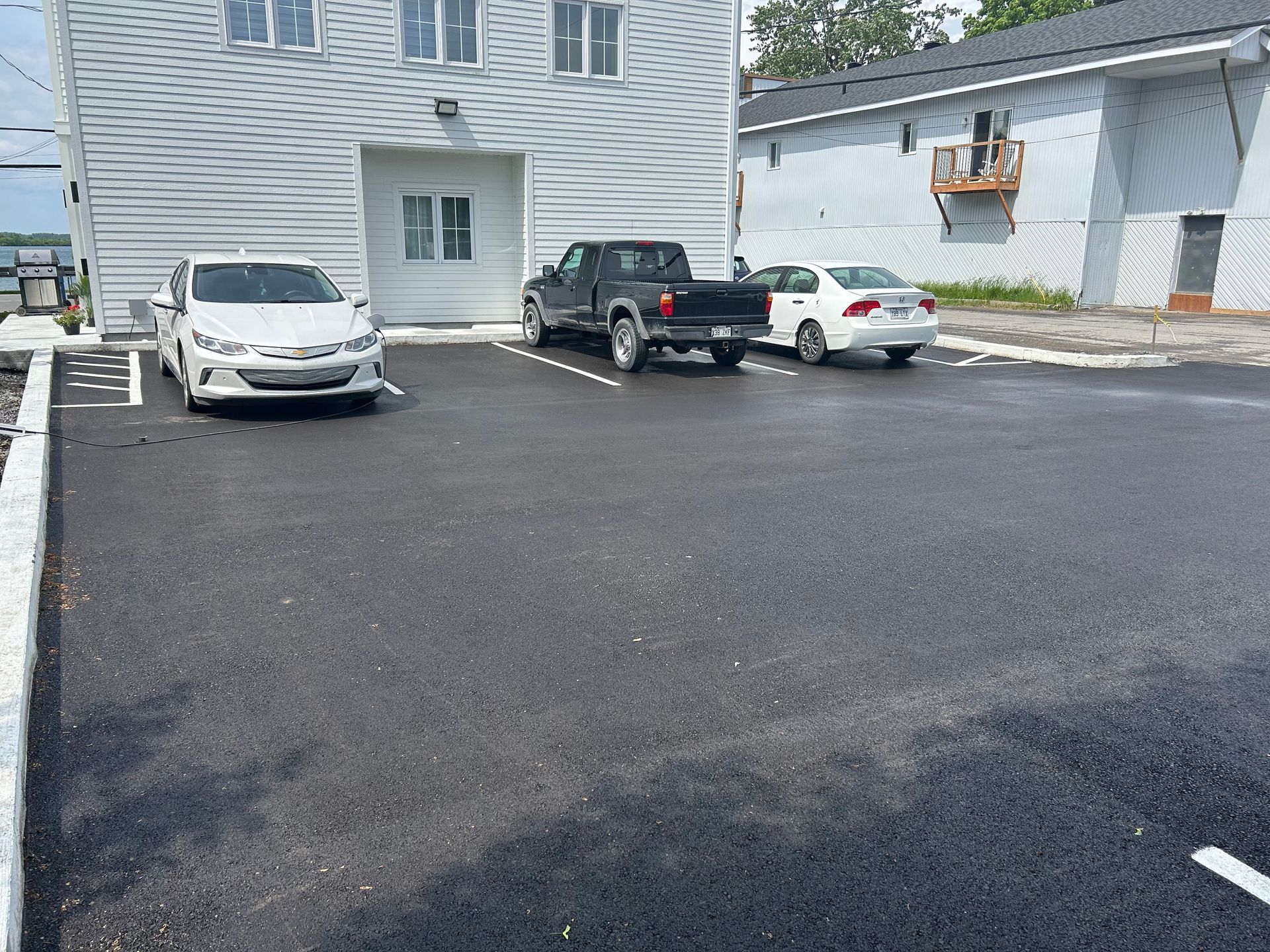 Un parking avec des voitures garées devant un immeuble