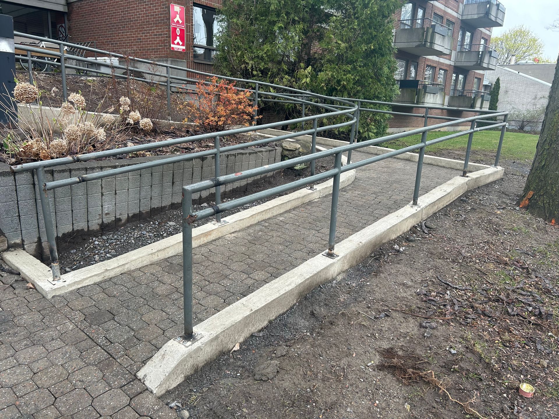 Une rampe pour handicapés avec une rampe métallique devant un bâtiment.