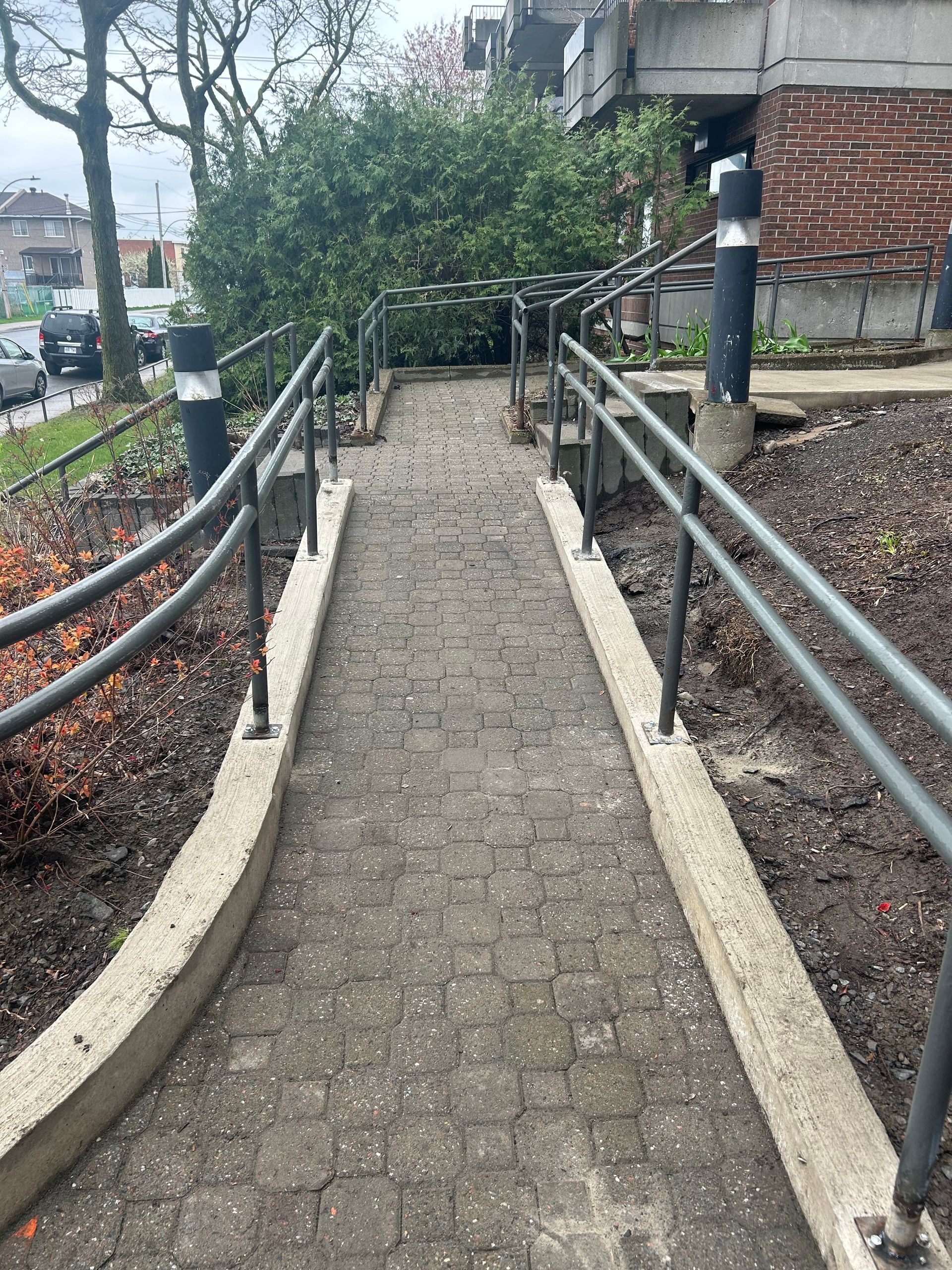 Une passerelle en brique avec des garde-corps métalliques menant à un bâtiment