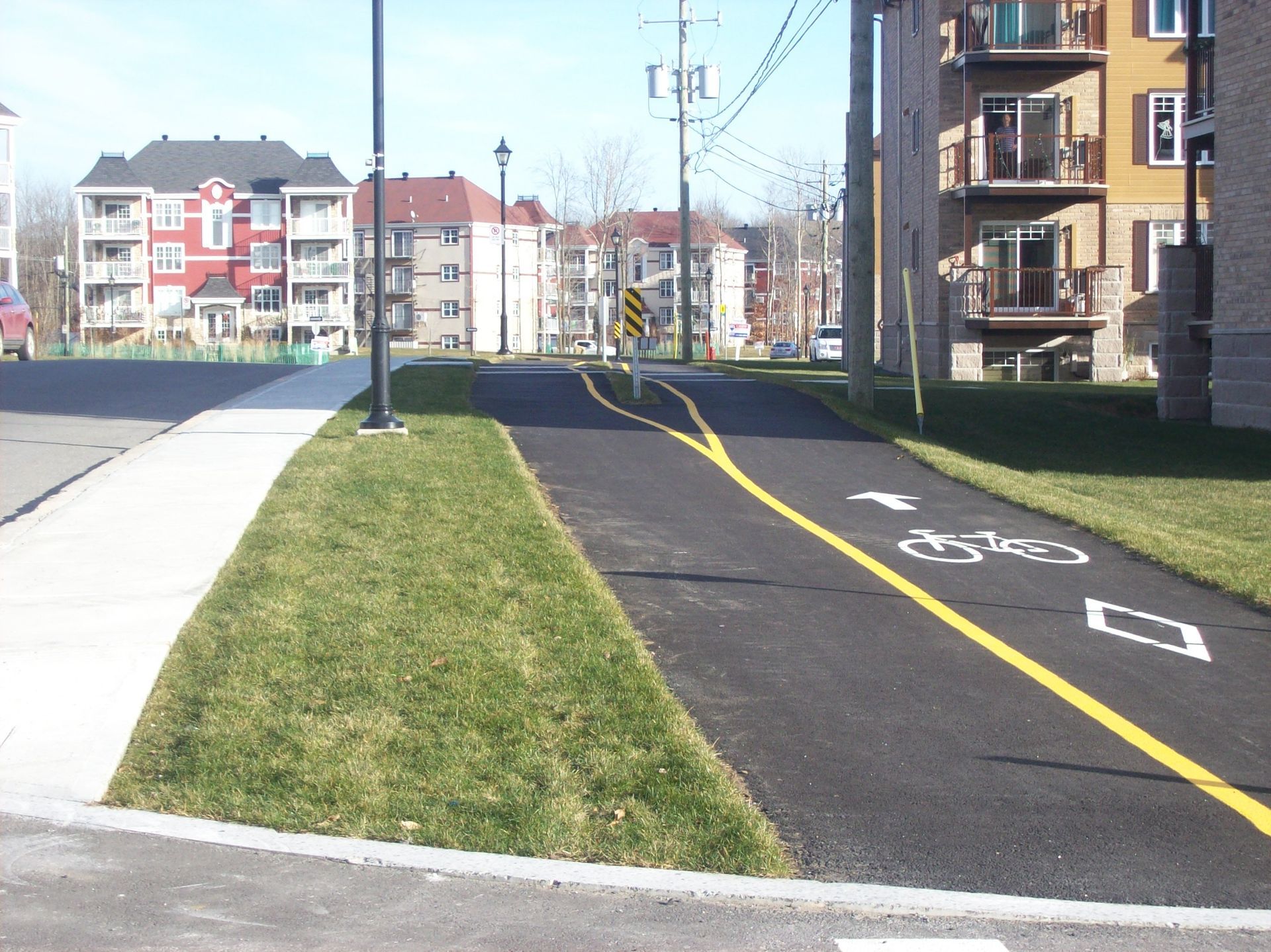 Une rue avec une piste cyclable et quelques immeubles en arrière-plan