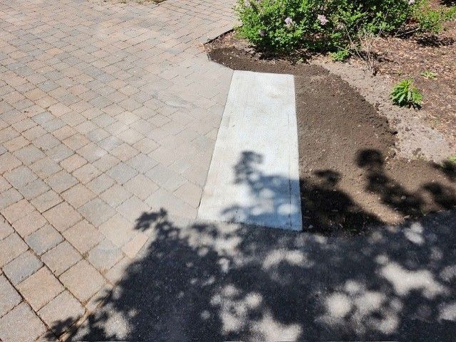 L'ombre d'un arbre est projetée sur une passerelle en brique.