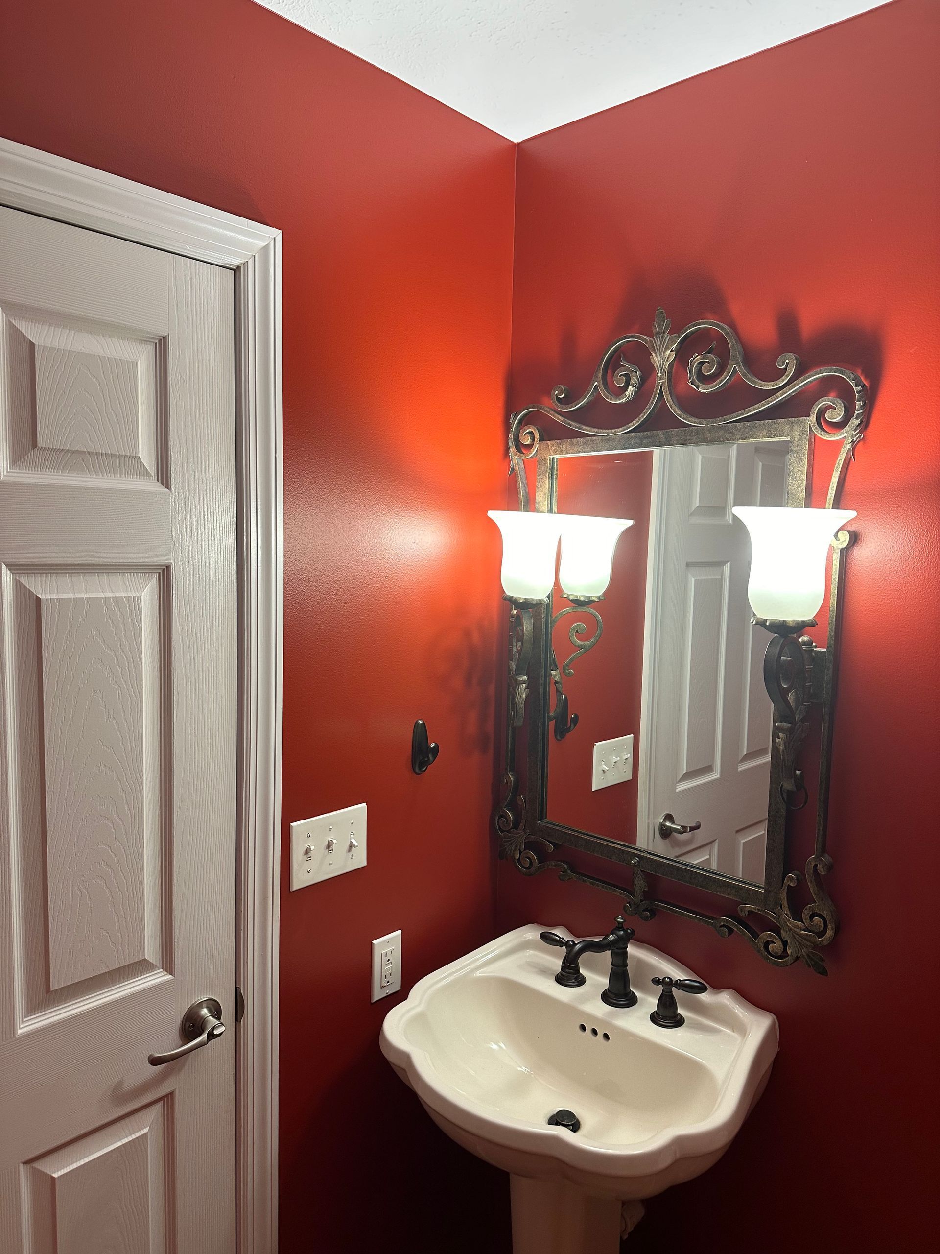 A bathroom with red walls and a sink and mirror