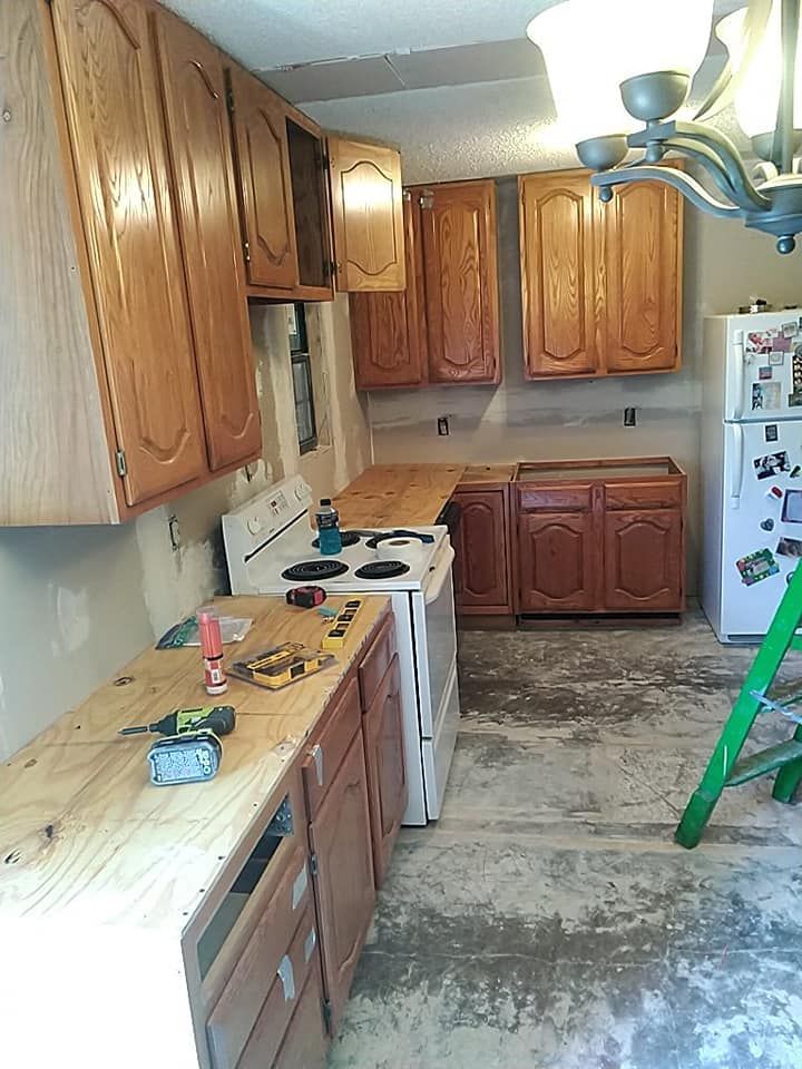 A kitchen with wooden cabinets , a stove , a refrigerator and a ladder.
