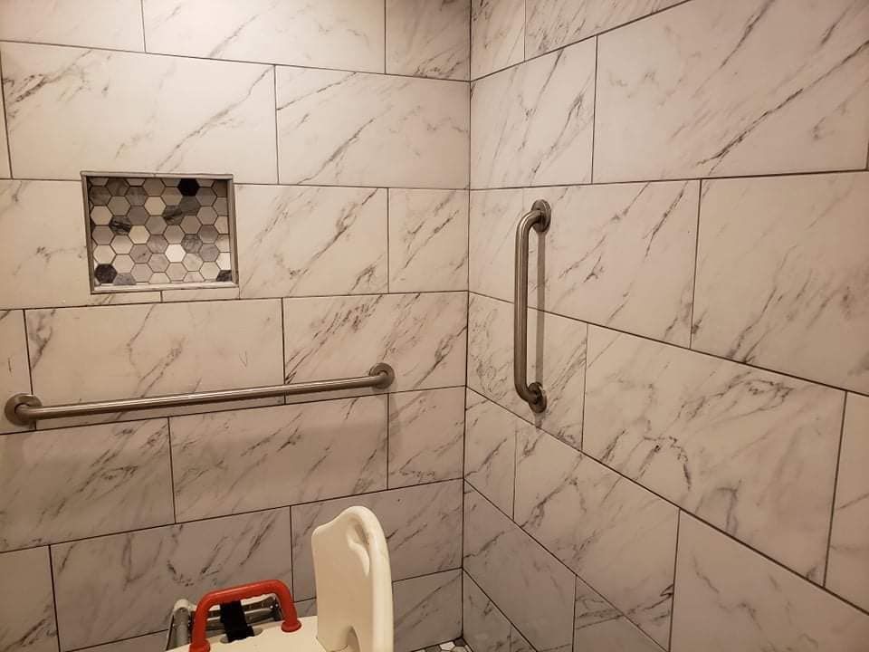 A bathroom with marble tiles and a stainless steel railing