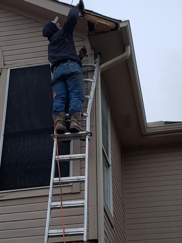 A man on a ladder working on the roof of a house