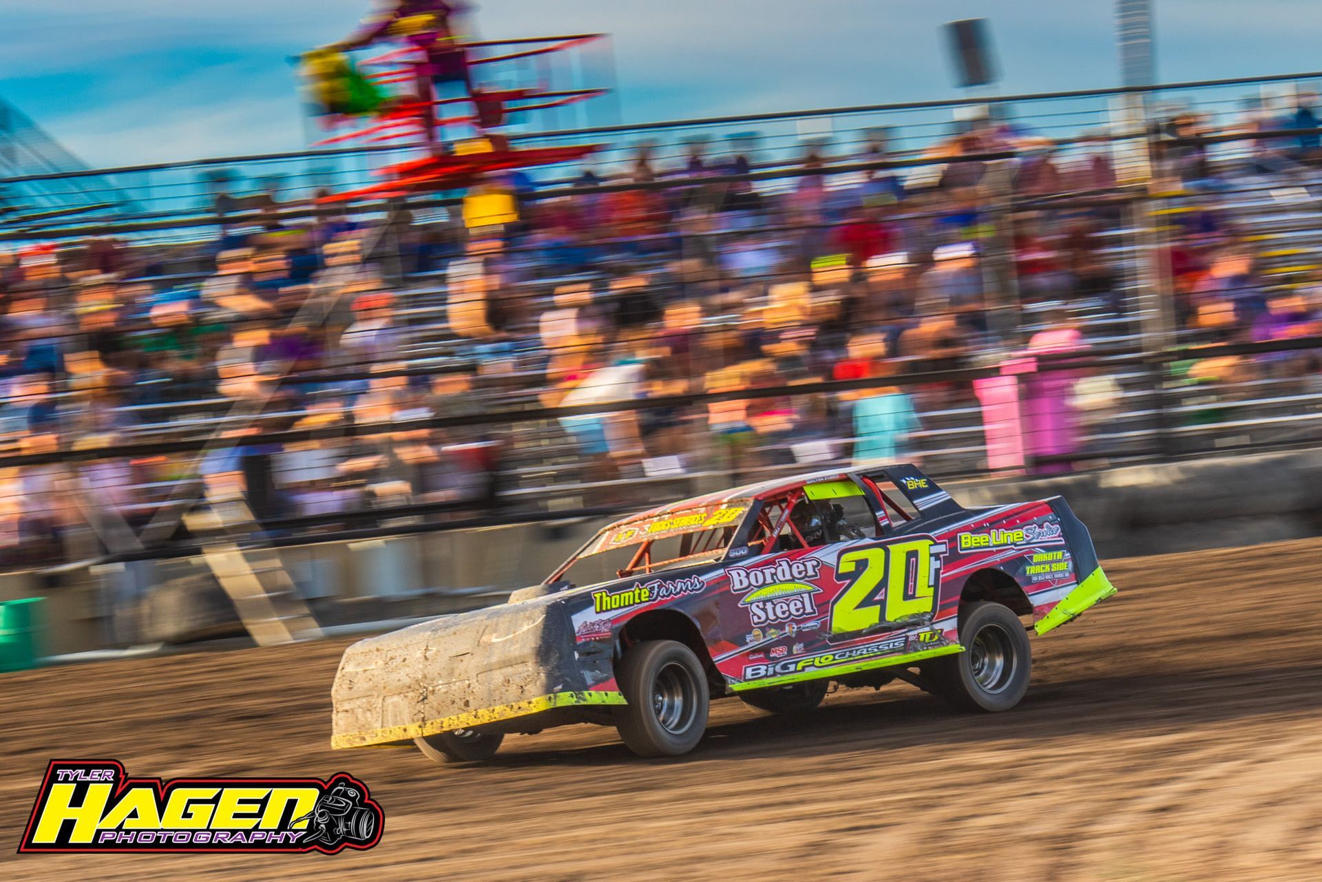Colorful race car speeding on a dirt track with blurred spectators in the background.