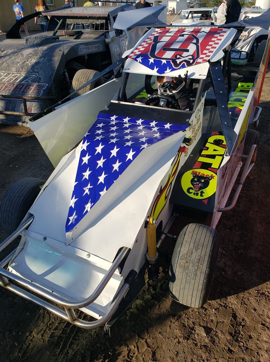 Decorated dirt track race car with American flag graphics on a dirt surface