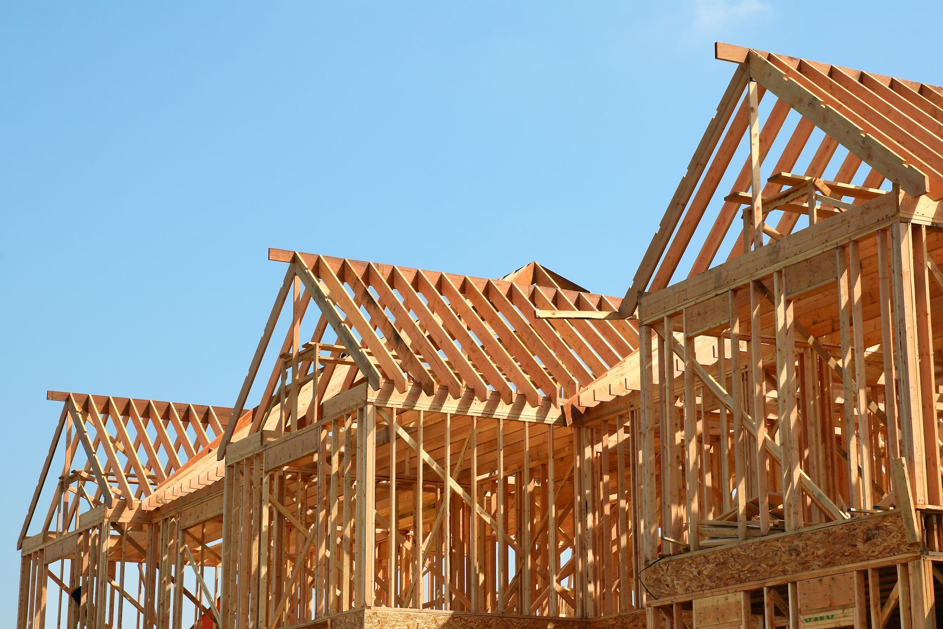 A row of wooden houses under construction with a blue sky in the background