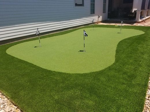 A backyard putting green with three holes and red flags. Beau Monde installed Lafayette, LA