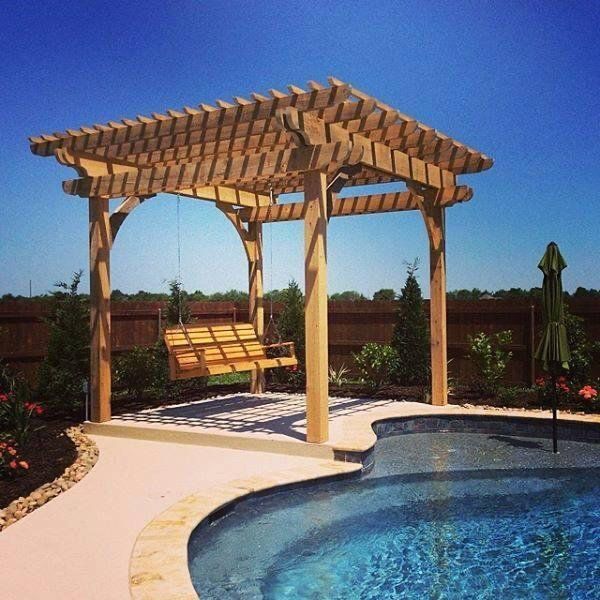 Wooden pergola with swing, set beside a pool. Sunny outdoor setting.