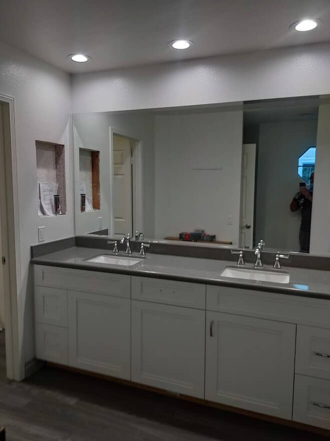 Bathroom with double sink vanity, large mirror, and recessed lighting. Gray countertop and white cabinets.