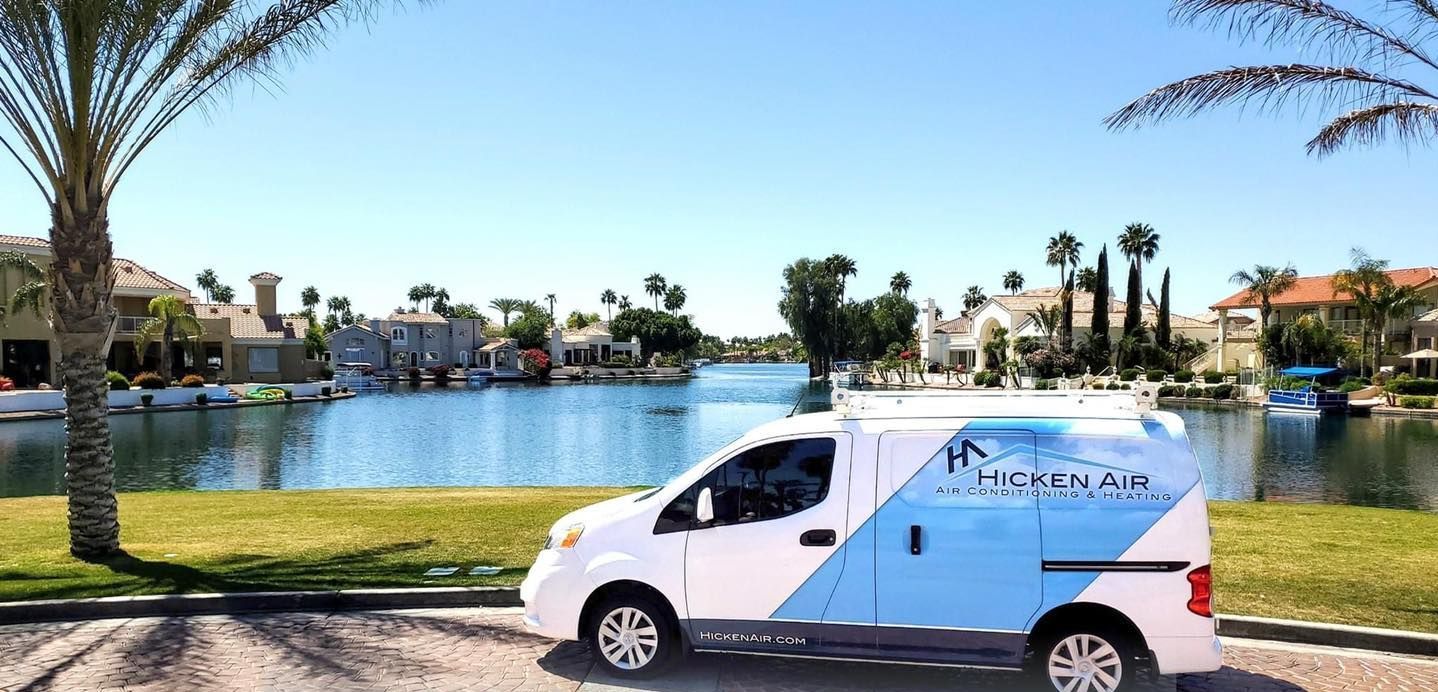 A white van is parked on the side of the road in front of a lake.