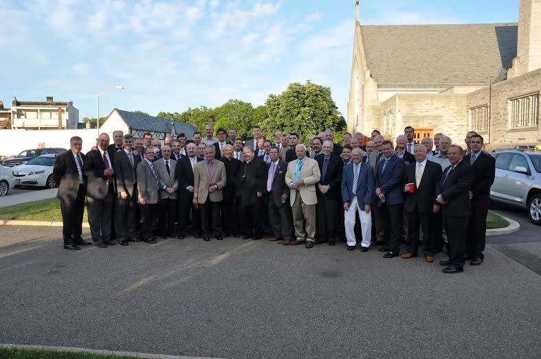 A large group of men are posing for a picture in front of a church