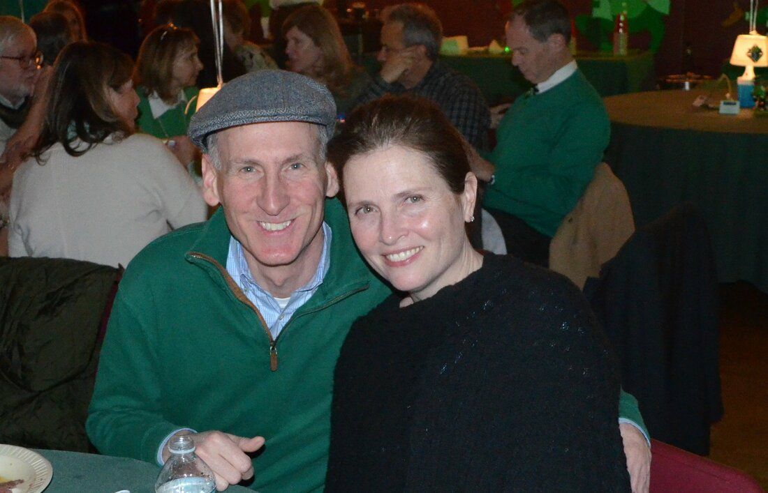 A man and a woman are posing for a picture while sitting at a table
