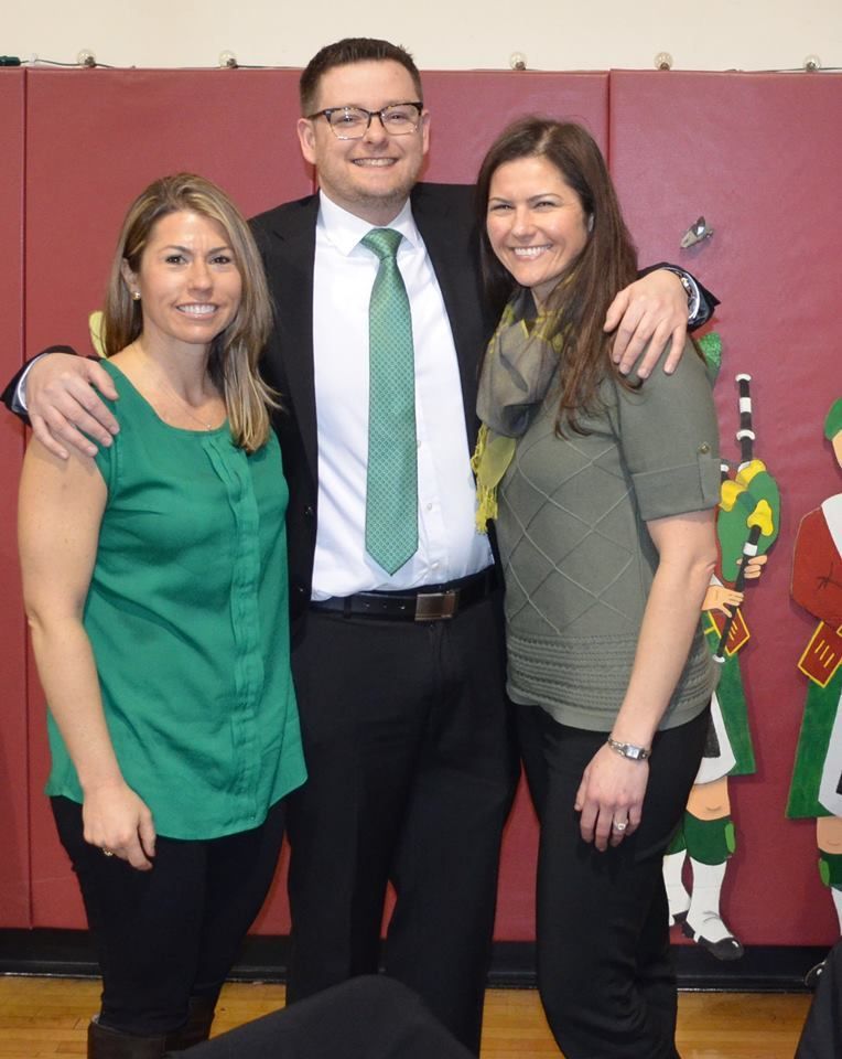 A man in a suit and tie poses with two women