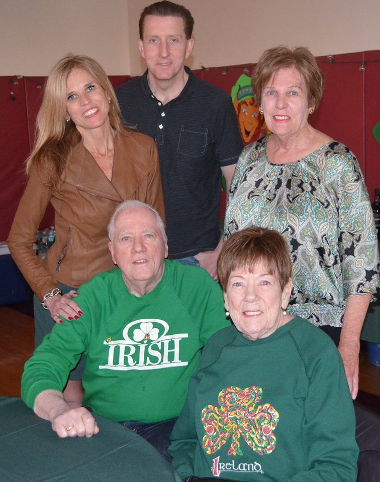 A group of people posing for a picture with one wearing a green irish shirt