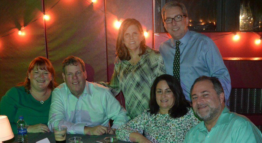 A group of people are posing for a picture while sitting at a table.