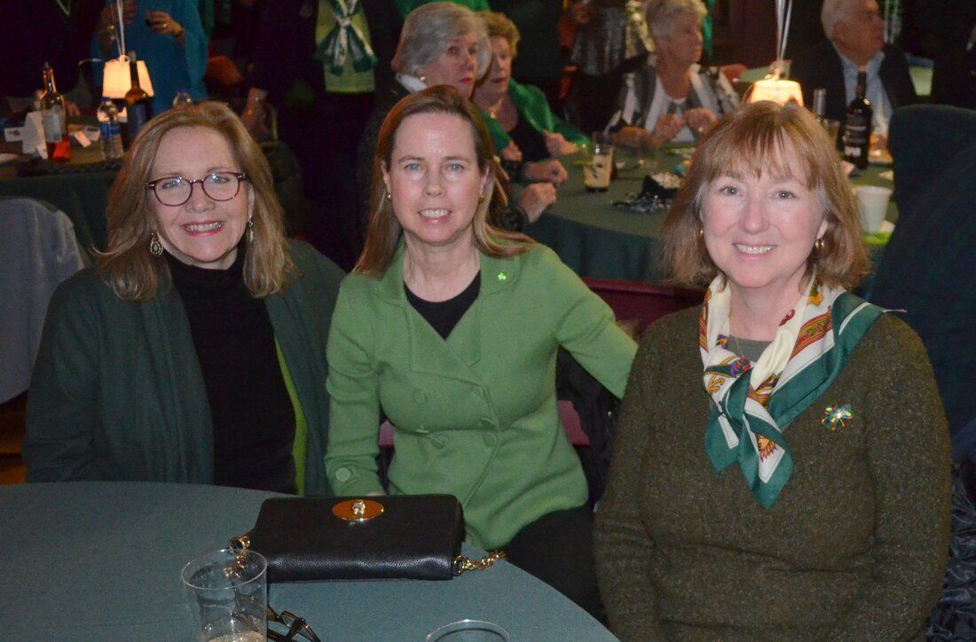Three women are posing for a picture while sitting at a table