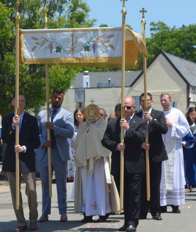 A group of people carrying a banner with grapes on it