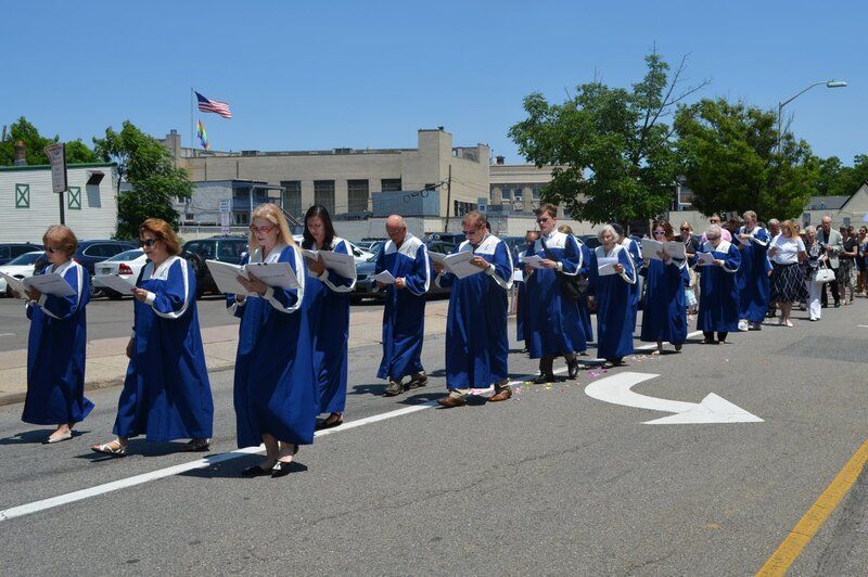 A group of people in blue gowns are marching down a street