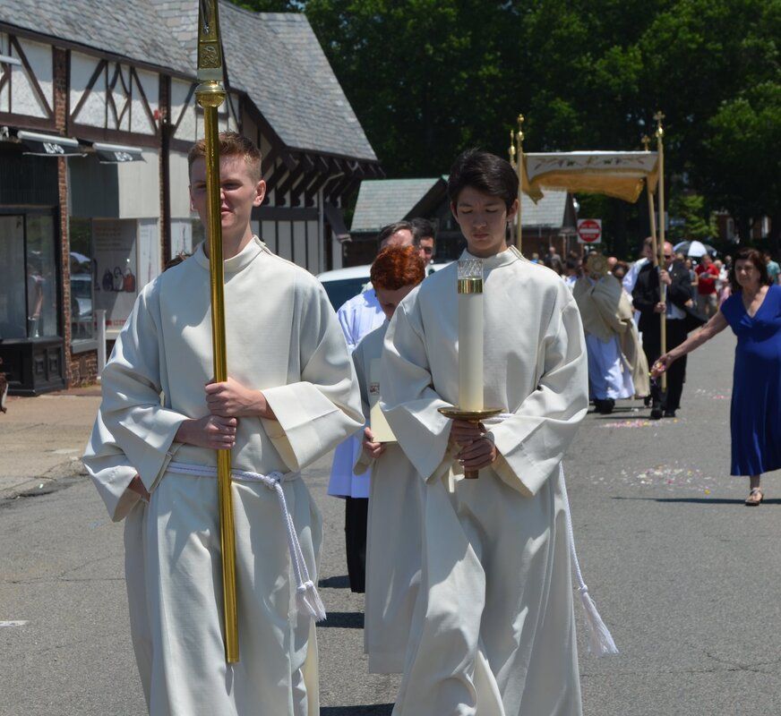 A group of people in white robes are walking down a street