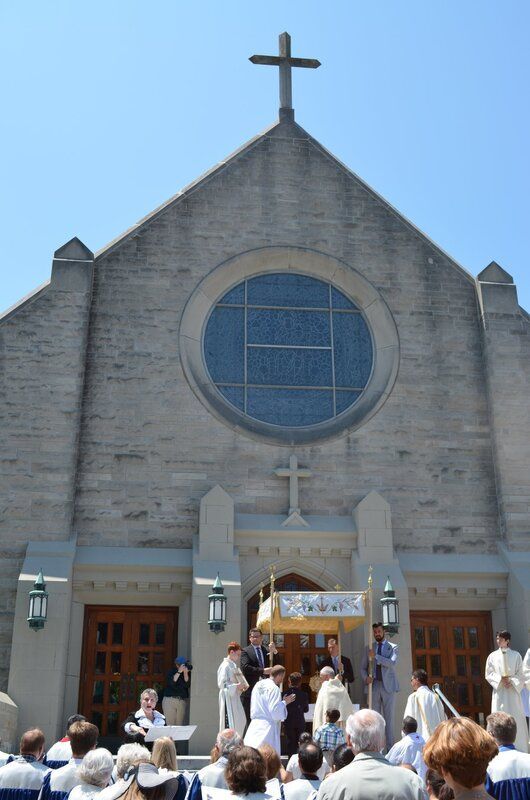 A group of people are gathered in front of a church with a cross on top