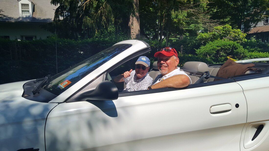 Two men are sitting in a white convertible car.