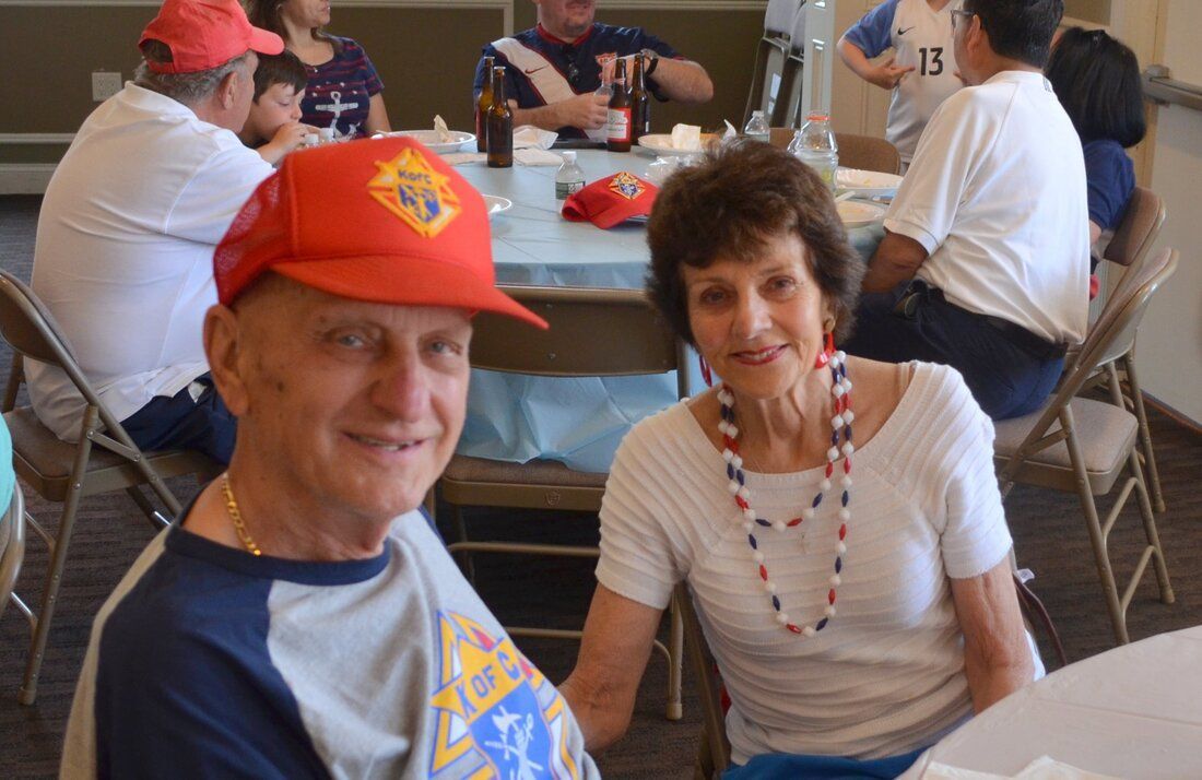 A man wearing a red hat is sitting next to a woman at a table.
