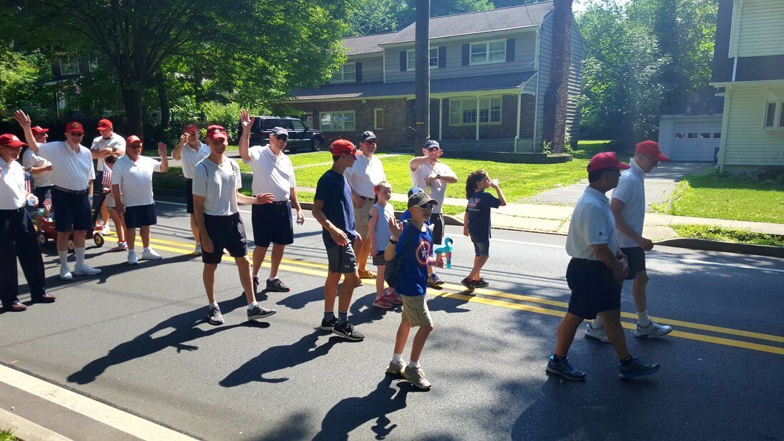 A group of people marching down a street in front of a house
