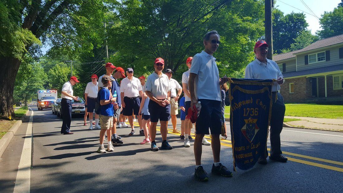 A group of people standing on the side of a road holding a banner that says 1776