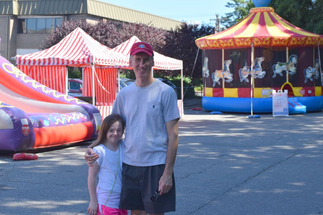 A man and a girl are posing for a picture in front of a carousel