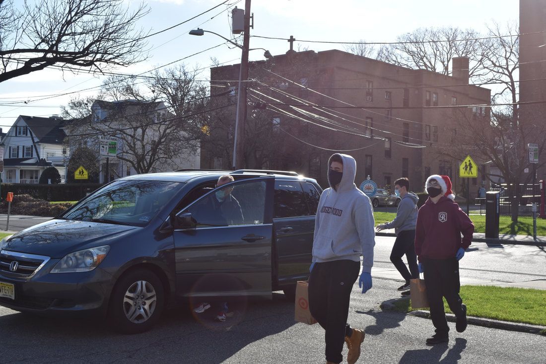 A group of people wearing masks are walking down a street in front of a van.