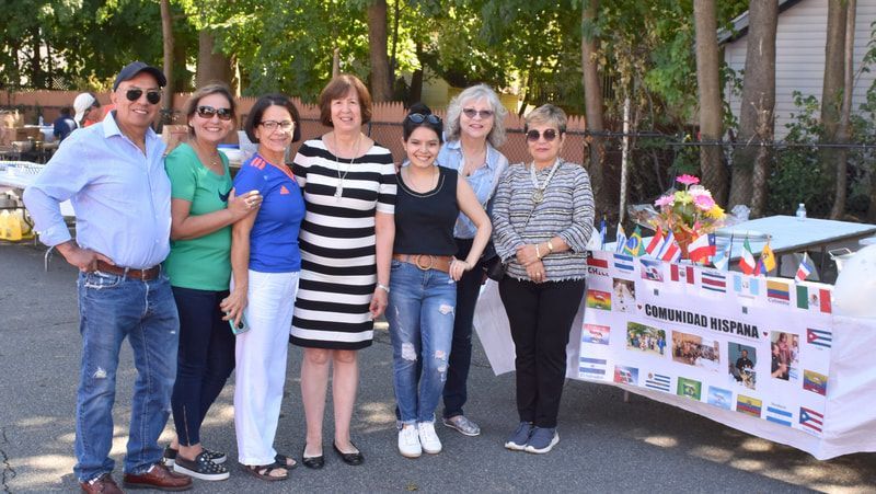 A group of people are posing for a picture in front of a table with flags on it.