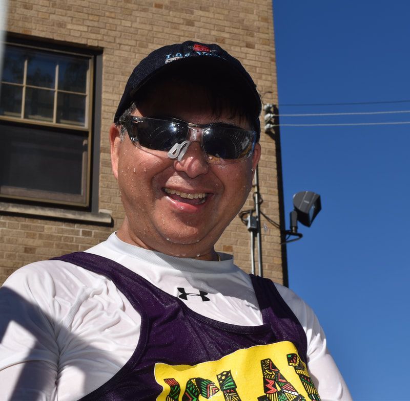 A man wearing a hat and sunglasses is smiling