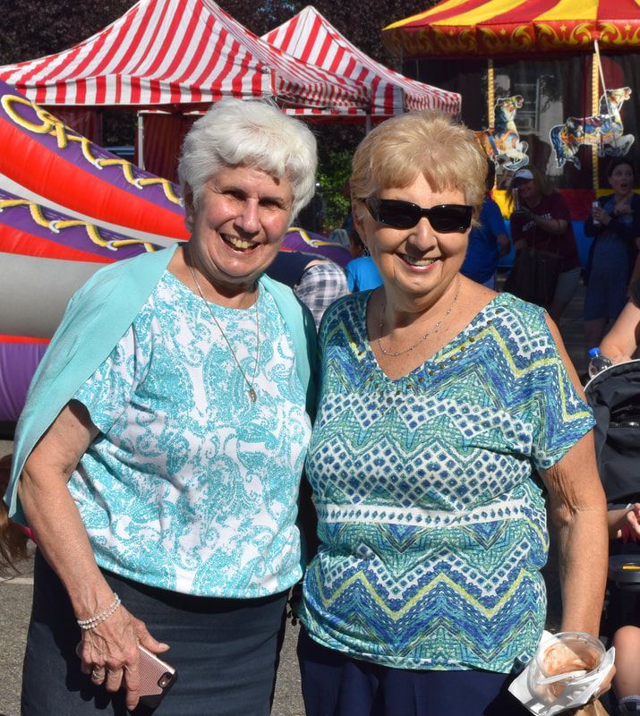 Two older women are posing for a picture at a carnival