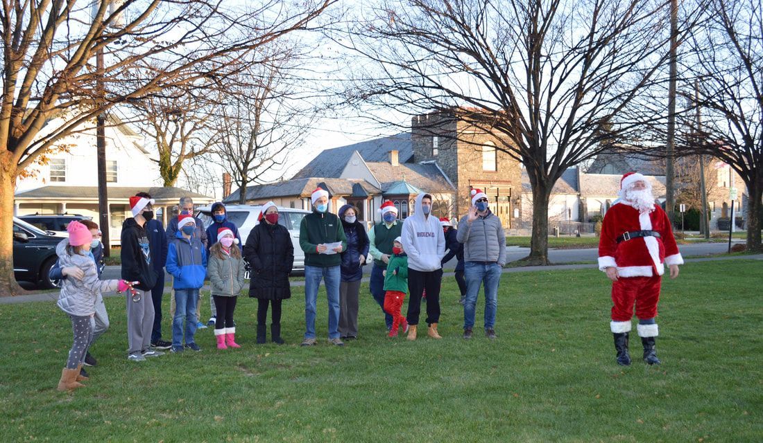 A group of people are standing in a park with santa claus.