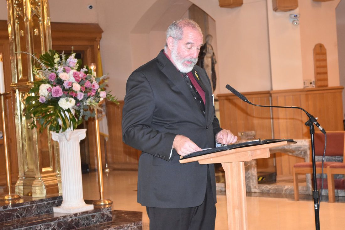 A man in a suit is standing at a podium in front of a microphone