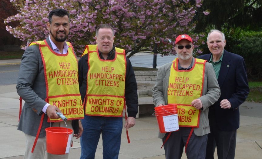 A group of men wearing yellow vests that say help handicapped citizens
