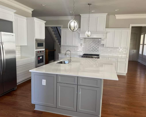 A modern kitchen featuring white cabinets, a gray center island with a white countertop, and stainless steel appliances.